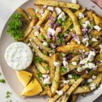 Close-up Greek fries golden crispy feta herb topping