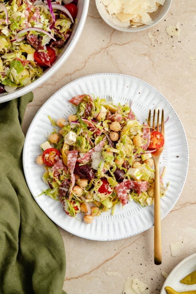 Italian Chopped Brussels Sprouts Salad Pinterest vertical image with large salad bowl and bold text overlay on clean white background
