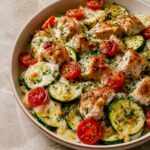 Close-up of Mediterranean Chicken Zucchini Bake showing juicy golden chicken pieces and colorful roasted vegetables with melted cheese