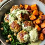 Herbed chicken meatball bowl with quinoa, fresh greens, cherry tomatoes, and balsamic dressing in a white bowl