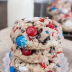 4th of July Cookie dough balls on a parchment-lined baking sheet with red white and blue MandMs and star sprinkles pressed on top before baking