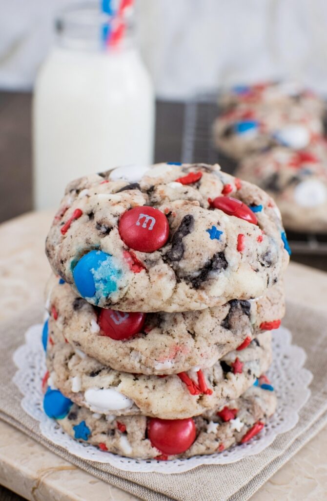 4th of July Cookie dough balls on a parchment-lined baking sheet with red white and blue MandMs and star sprinkles pressed on top before baking