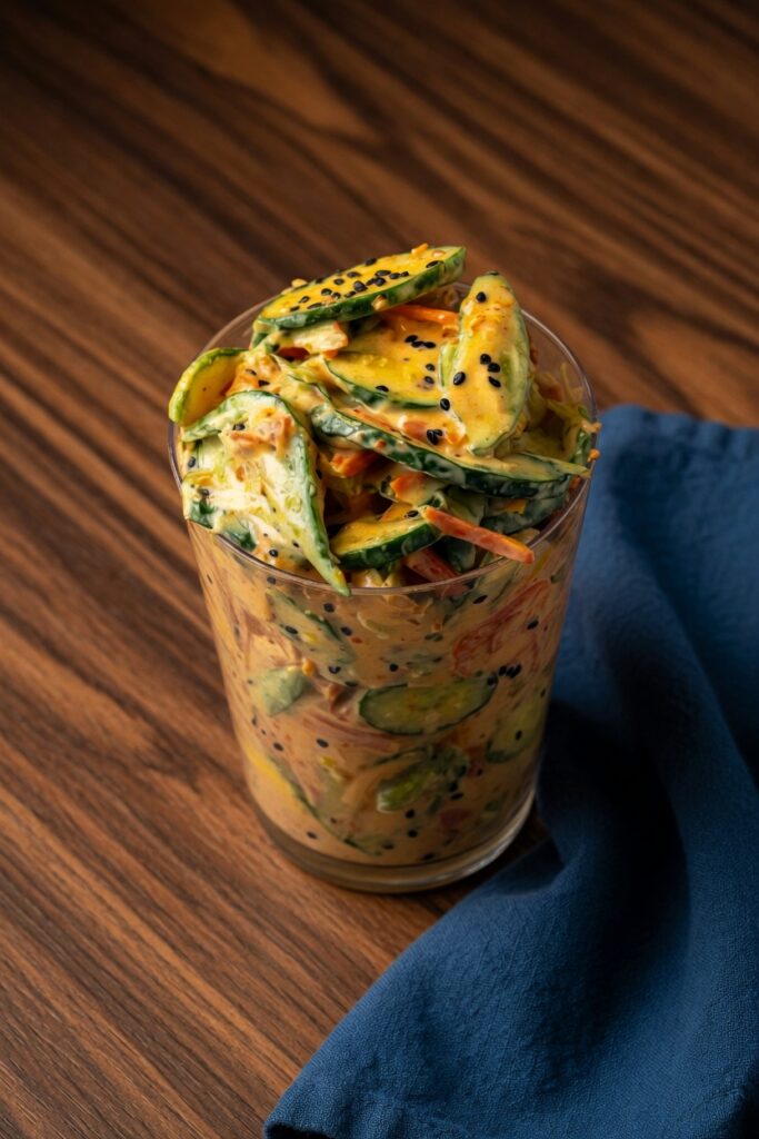 Creamy spicy Asian dressing for Viral Creamy Asian Cucumber Salad being whisked in a small white bowl with Sriracha chili oil and soy sauce visible